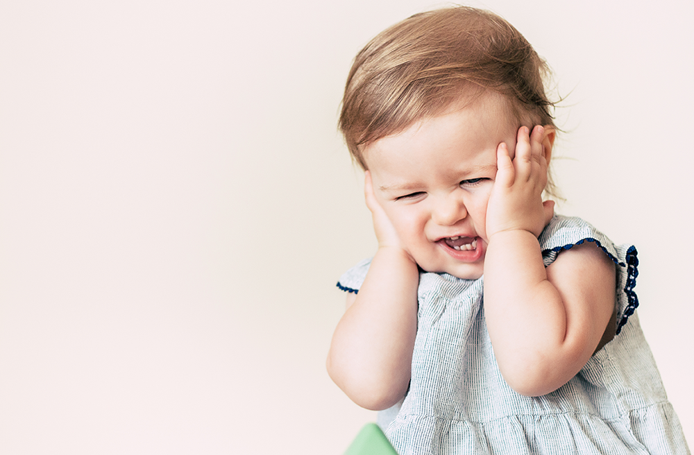 Photo of a toddler holding her ears in pain