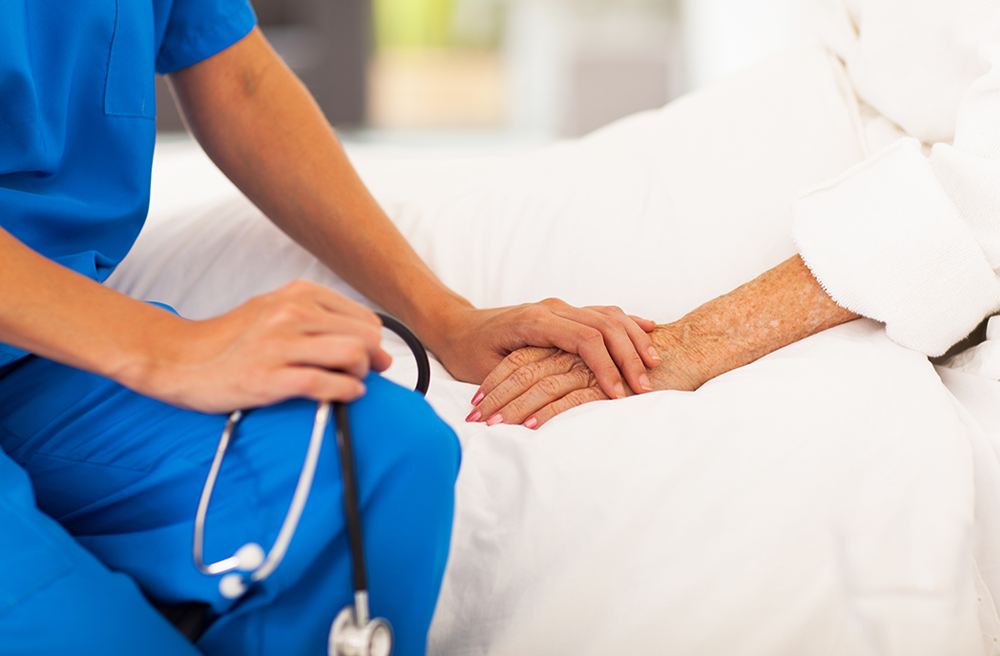 Photo of a nurse holding the hand of an elderly patient