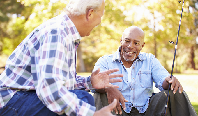 Photo of two older men talking while fishing